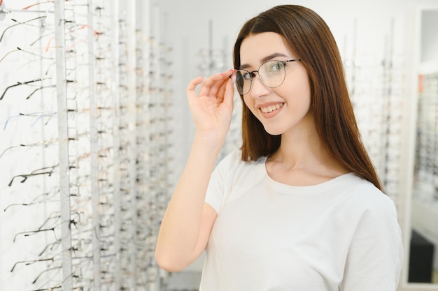 Jonge vrouw met bril in optische winkel Mooi meisje met bril in opticien winkel