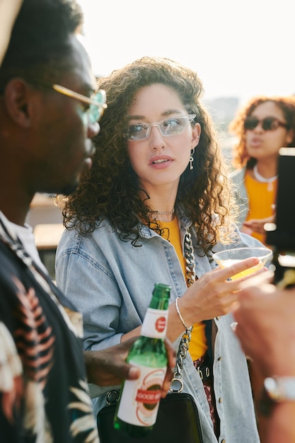 Jonge vrouw met cocktail kijken naar Afro-Amerikaanse man met flesje bier