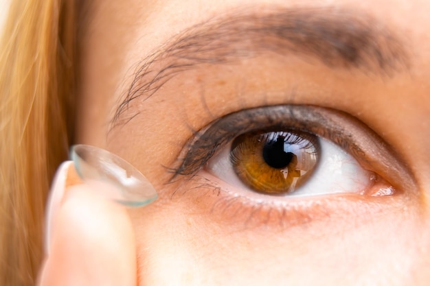 Jonge vrouw met contactlens in de buurt van haar bruine oog