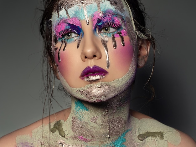 Jonge vrouw met creatieve kunst make-up portret Gebarsten huid en gouden tranen Mode salon make-up