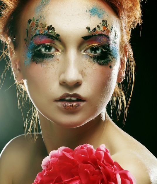 Foto jonge vrouw met creatieve make-up met grote roze bloem