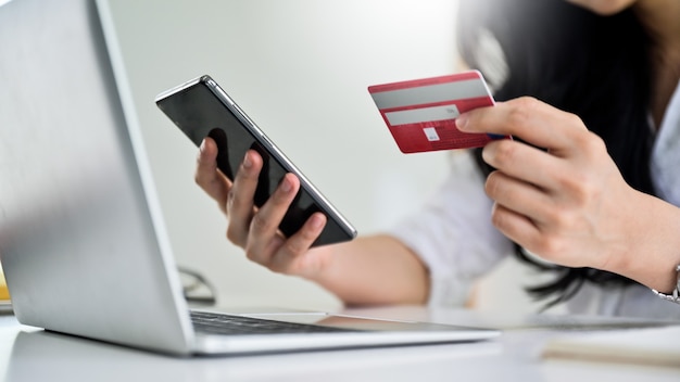 Jonge vrouw met creditcard en smartphone met laptop, online winkelconcept, creditcardbetaling.