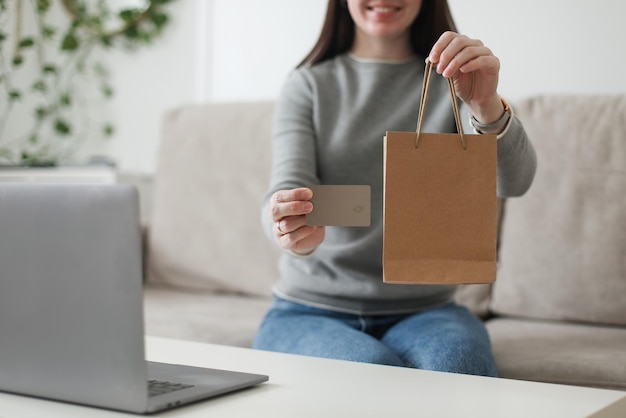 Jonge vrouw met creditcard en thuis met behulp van laptop Online thuiswinkelen internetbankieren elektronisch winkelconcept