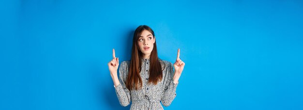 Foto jonge vrouw met de armen omhoog tegen een blauwe achtergrond