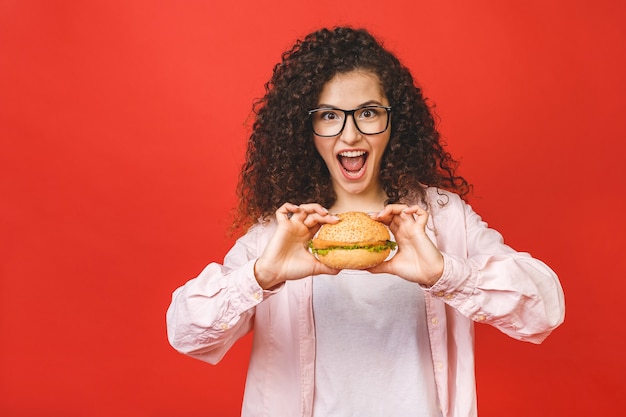 Jonge vrouw met de hamburger van de krullend haarholding