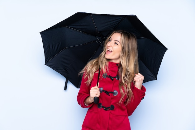 Jonge vrouw met de winterjas en holding een paraplu die een overwinning viert