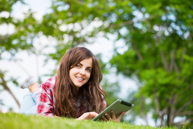 Jonge vrouw met digitale tablet op het gras