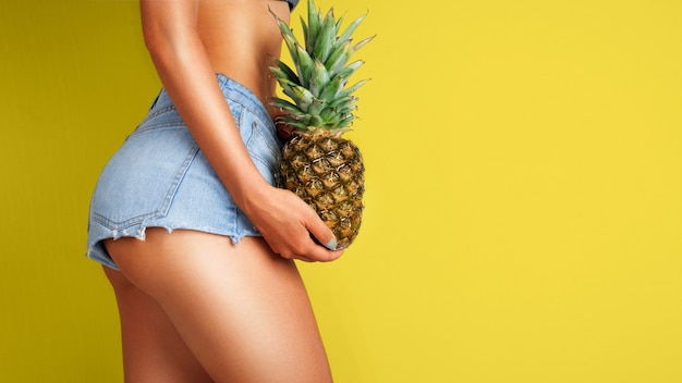 Jonge vrouw met een ananas in haar hand op een achtergrond in kleur