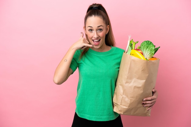 Jonge vrouw met een boodschappentas die een telefoongebaar maakt Bel me terug-teken