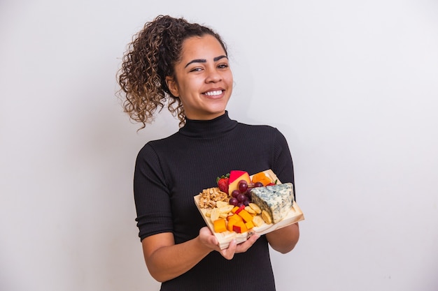 Jonge vrouw met een bord met verschillende soorten snacks kaas.