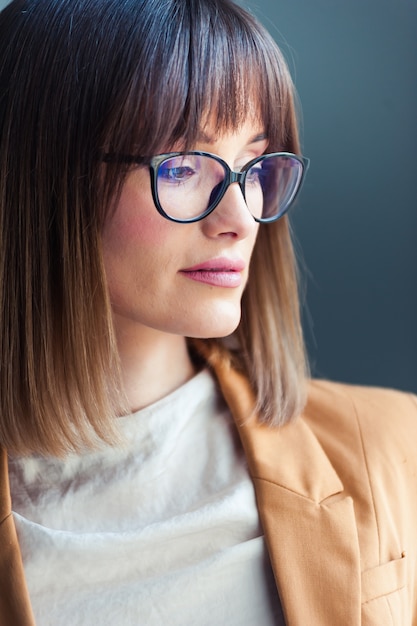 jonge vrouw met een bril, gekleed als casual op grijs