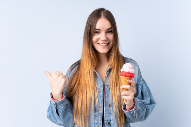 Jonge vrouw met een cornet ijs op blauwe muur wijst naar de zijkant om een product te presenteren