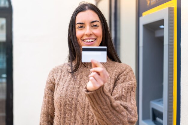 Jonge vrouw met een creditcard buitenshuis met een gelukkige uitdrukking