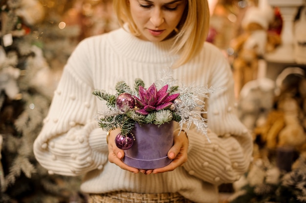 Jonge vrouw met een doos met groene succulent bedekt met roze glitter versierd met ornamenten