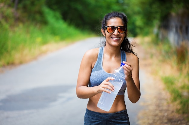 jonge vrouw met een fles in het bos