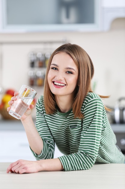 Jonge vrouw met een glas water in de keuken