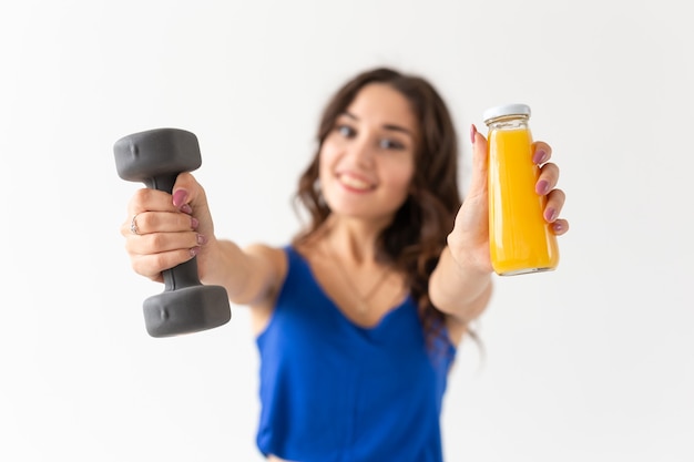 jonge vrouw met een halter in haar hand en een fles