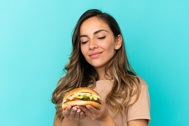 Jonge vrouw met een hamburger over geïsoleerde achtergrond