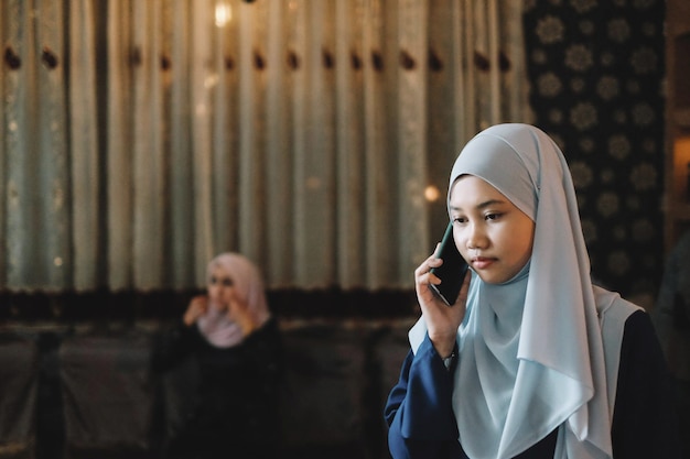 Jonge vrouw met een hijab terwijl ze een mobiele telefoon beantwoordt in de stad