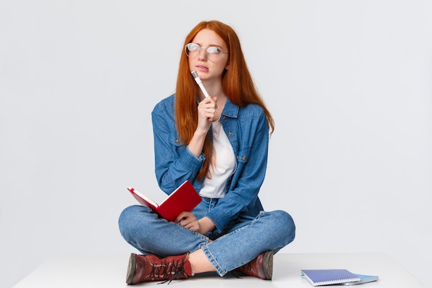 Jonge vrouw met een hoed die tegen een witte achtergrond zit
