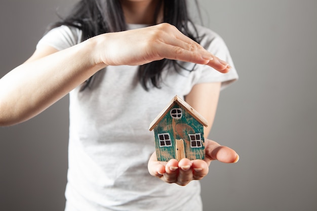 Jonge vrouw met een huis in haar handen