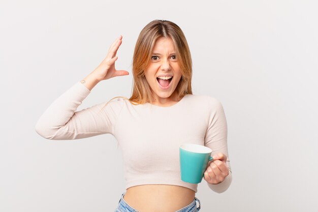 Jonge vrouw met een koffiemok schreeuwend met handen omhoog in de lucht