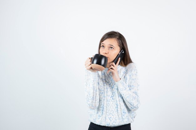 Jonge vrouw met een kop warme koffie en praten over de telefoon