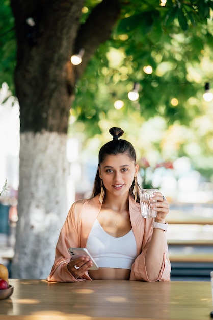 Jonge vrouw met een koud drankje zittend in een café op straat