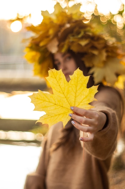 Jonge vrouw met een krans van gele herfstbladeren. Buiten portret. Herfst.