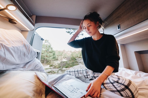 Jonge vrouw met een laptop in een camper.