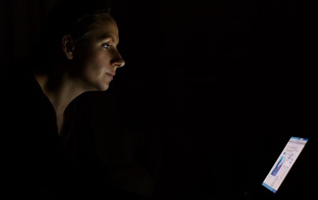 Foto jonge vrouw met een laptop laat in de nacht.