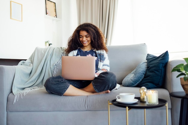Jonge vrouw met een laptop terwijl ze thuis op de bank zit