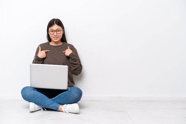 Jonge vrouw met een laptop zittend op de vloer met verrassing gezichtsuitdrukking