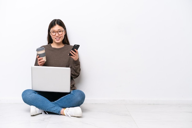 Jonge vrouw met een laptop zittend op de vloer