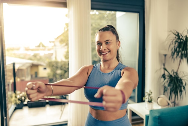 Jonge vrouw met een maatje meer die 's ochtends thuis traint met een rubberen band.