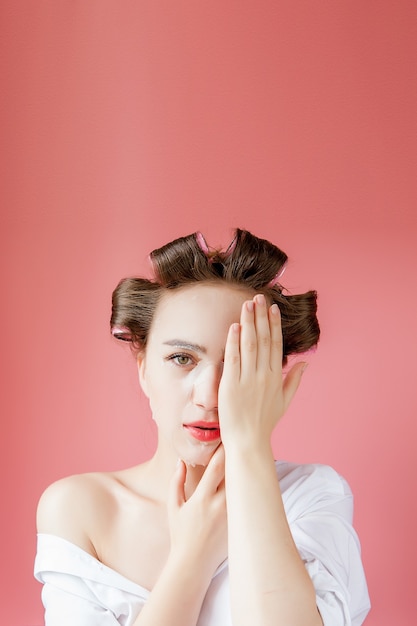 Jonge vrouw met een masker en krulspelden wat betreft haar gezicht.