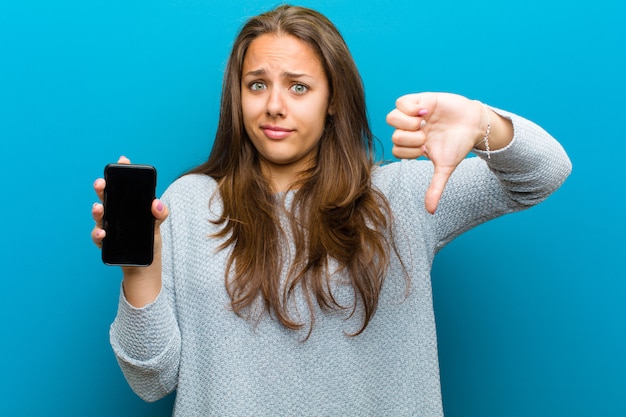 Jonge vrouw met een mobiele telefoon tegen blauwe achtergrond