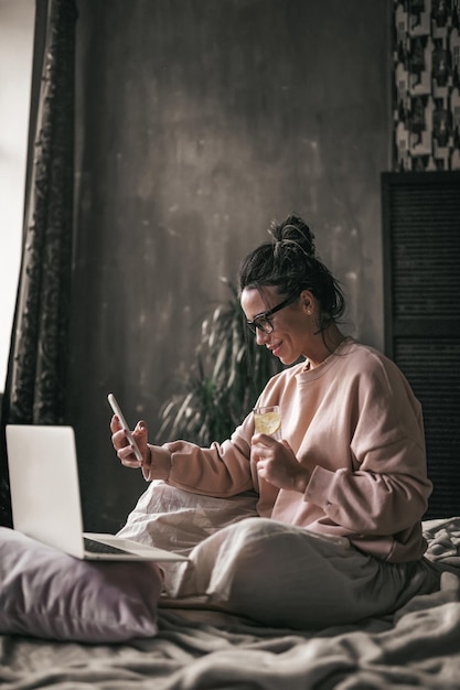 Jonge vrouw met een mobiele telefoon terwijl ze in een laptop zit