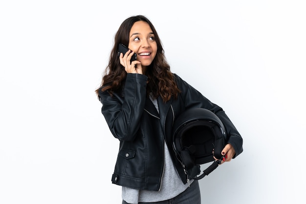 Jonge vrouw met een motorhelm over een geïsoleerde witte achtergrond met koffie om mee te nemen en een mobiel