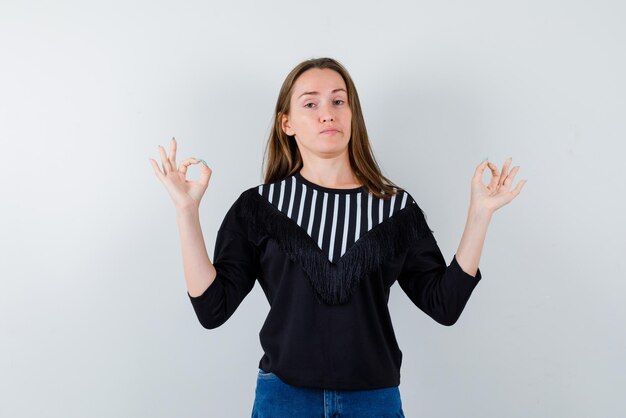 Jonge vrouw met een OK handgebaar op witte achtergrond