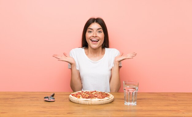 Jonge vrouw met een pizza met geschokte gelaatsuitdrukking