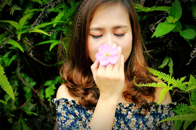 Foto jonge vrouw met een roze bloem tegen planten