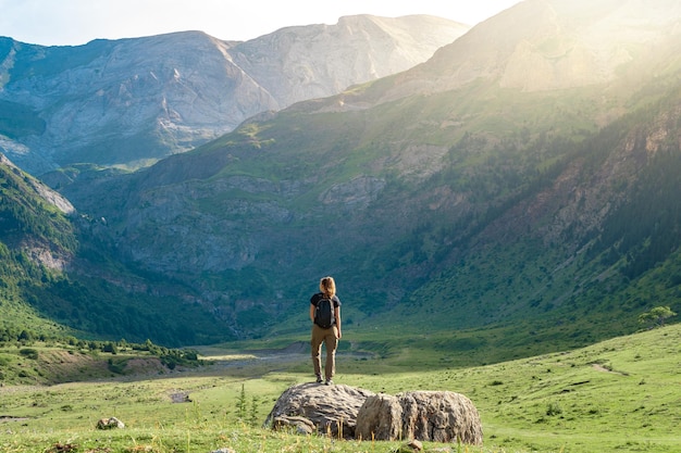 Jonge vrouw met een rugzak op de top van een rots in een prachtig wild landschap ontdekkingsreis