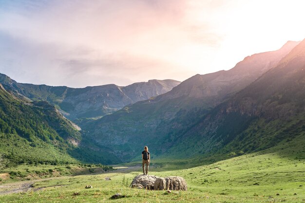 Foto jonge vrouw met een rugzak op de top van een rots in een prachtig wild landschap ontdekkingsreis