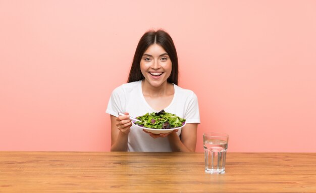 Jonge vrouw met een salade in een tafel