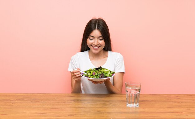 Jonge vrouw met een salade in een tafel