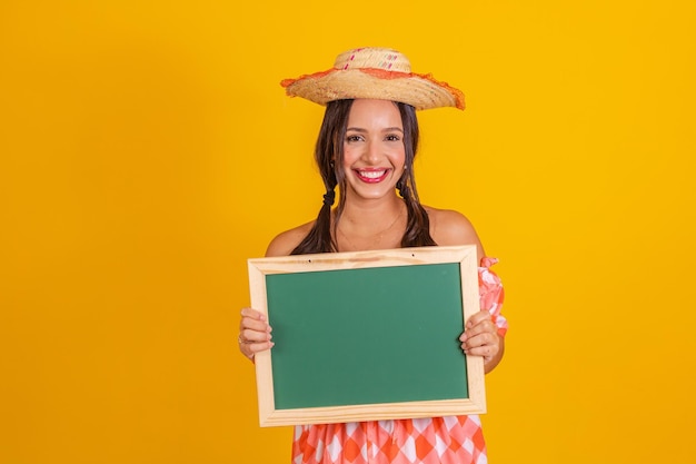 Jonge vrouw met een schoolbord met kopieerruimte juni-feest vrouw met festa junina-kleding, typisch braziliaans feest