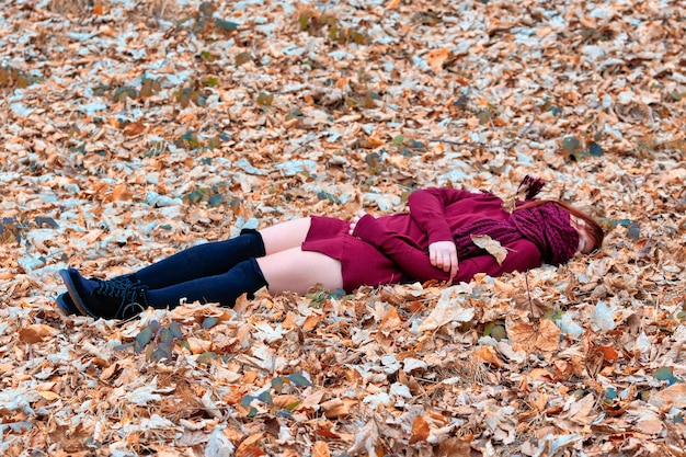 Foto jonge vrouw met een sjaal dat haar gezicht bedekt op herfstbladeren op het veld