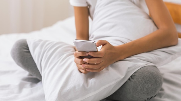 Foto jonge vrouw met een smartphone en rusten in bed