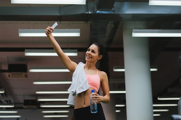 Jonge vrouw met een smartphone selfie te nemen in de sportschool